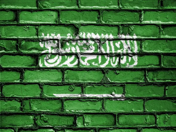 علم المملكة العربية السعودية مرسوم على جدار من الطوب، خلفية لشراء العملات الرقمية في المملكة